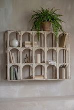 Load image into Gallery viewer, A distressed white wooden wall shelf with 16 arched compartments, styled with potted green plants, ceramic pots, a small birdhouse, and books against a beige wall.