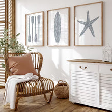 Load image into Gallery viewer, Living room with wicker chair, white cabinet, and framed artwork on the wall.
