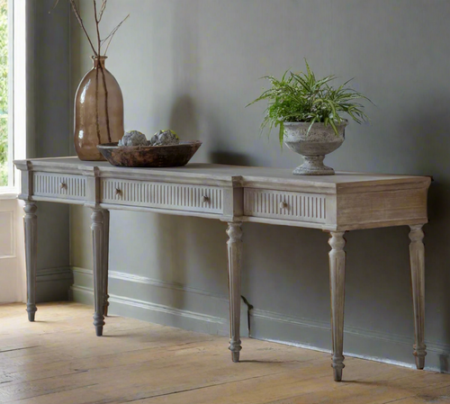 Wooden console table with decorative items against a plain wall