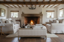 Load image into Gallery viewer, A cream tufted upholstered storage bench with a light wood frame and legs, styled in a bedroom setting with a wooden tray, books, and a small vase on top.
