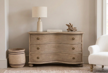 Load image into Gallery viewer, A distressed light brown wooden chest of drawers with three curved drawers and round brass knobs, styled in a bedroom setting with decorative items on top.
