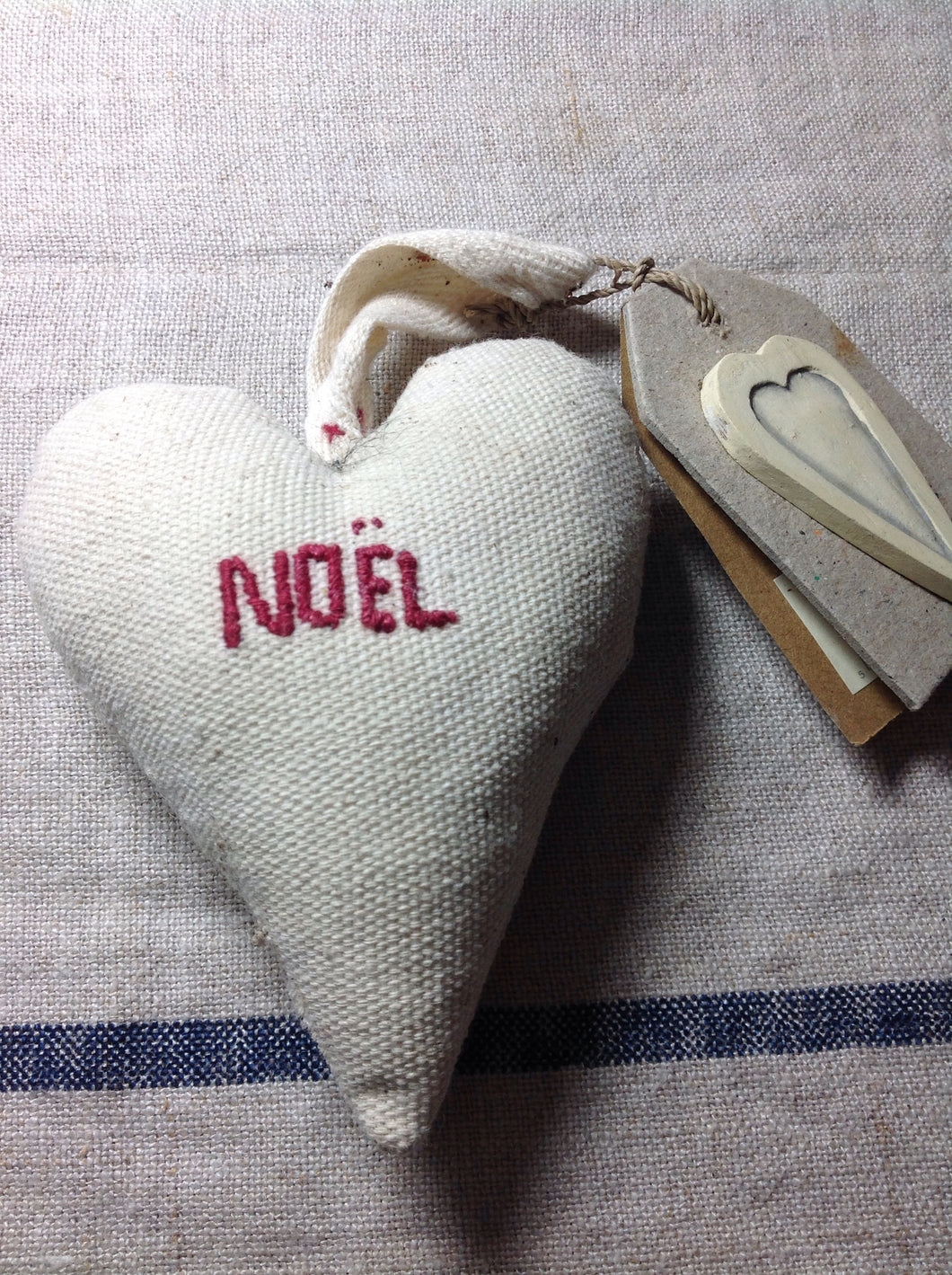 Cream hanging Christmas decoration heart with Noel embroidered on the front.